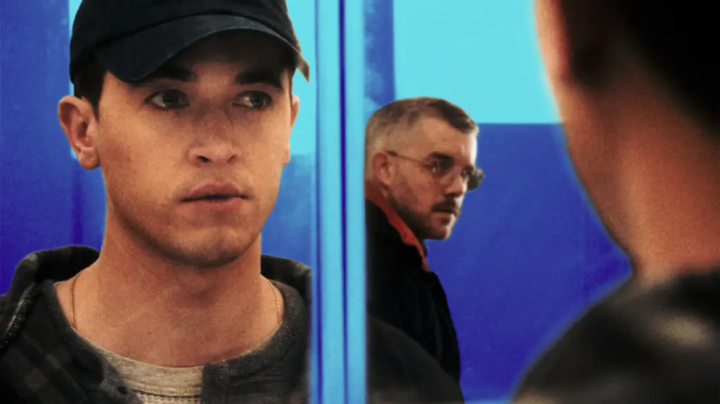 A stylized film still featuring two men against a backdrop of vibrant blue and teal lighting.