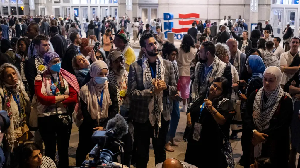 Group of people standing outside a convention center in the evening.