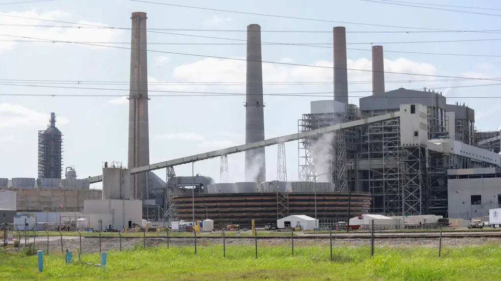 A power plant with four big smokestacks and green grass in foreground