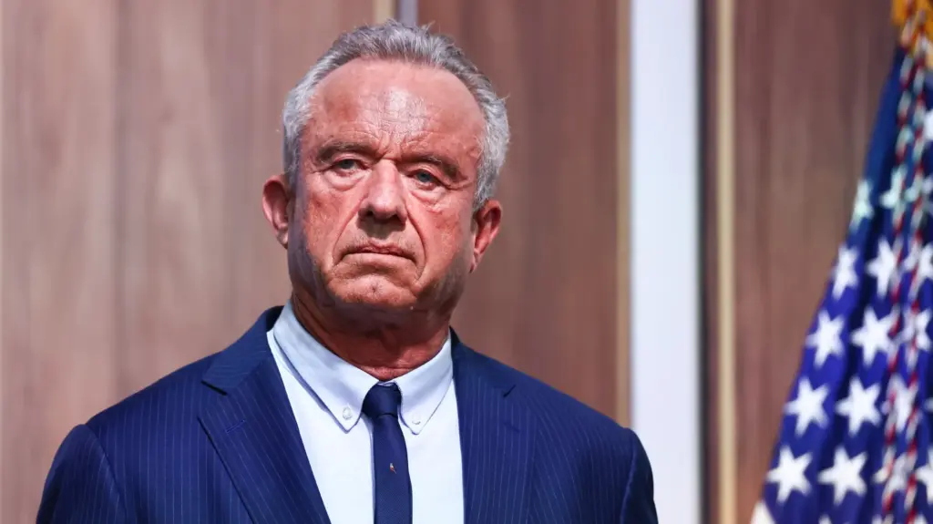 Robert Kennedy Jr. stands next to a US flag.