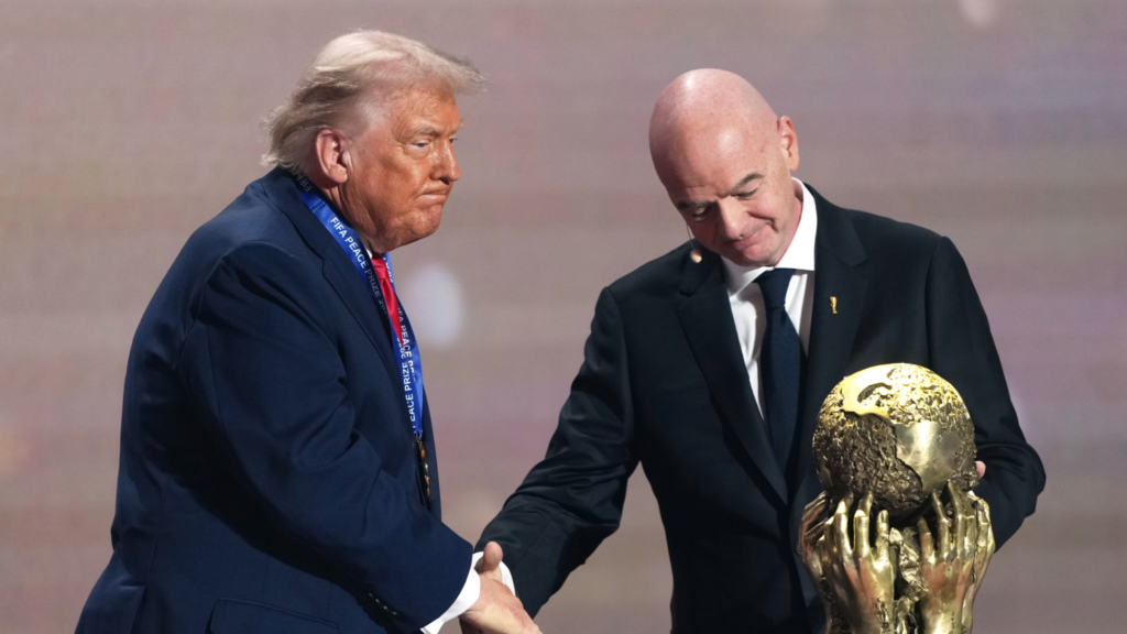 Donald Trump and Gianni Infantino shake hands behind a golden trophy labeled, in part, 
