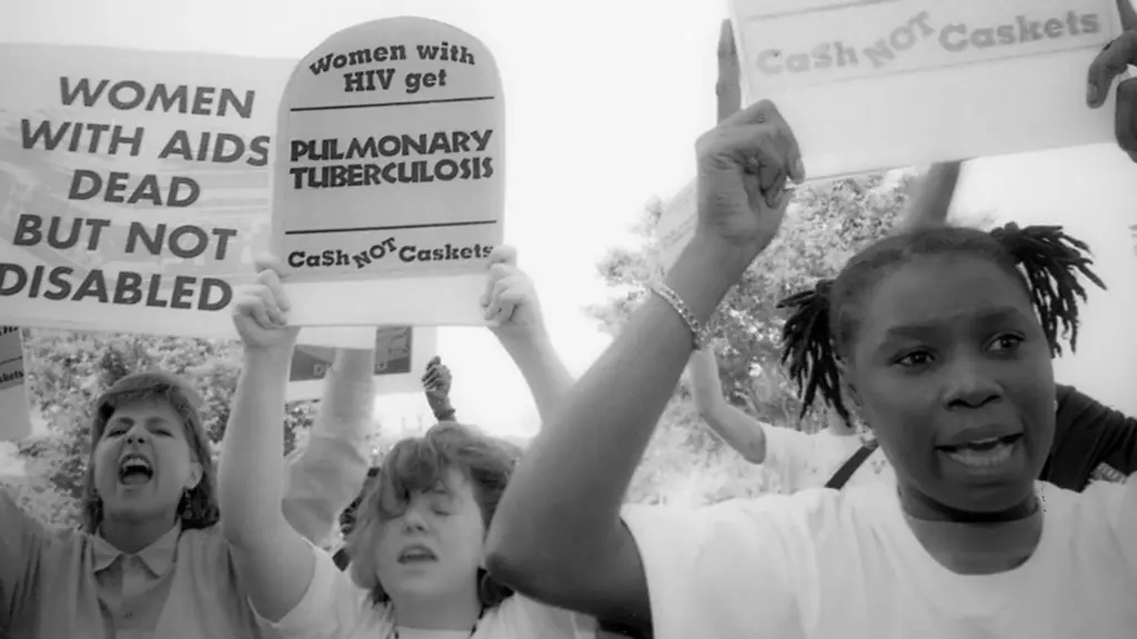 Three women hold signs that read: 