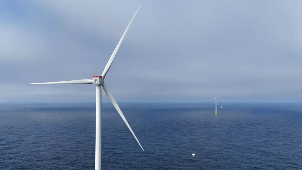a row of wind turbines stretching over the blue ocean, very far apart.