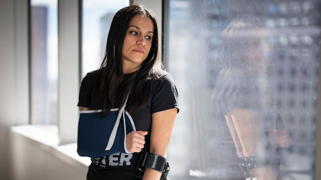 Aliya Rahman leans against a window, her arm in a sling.