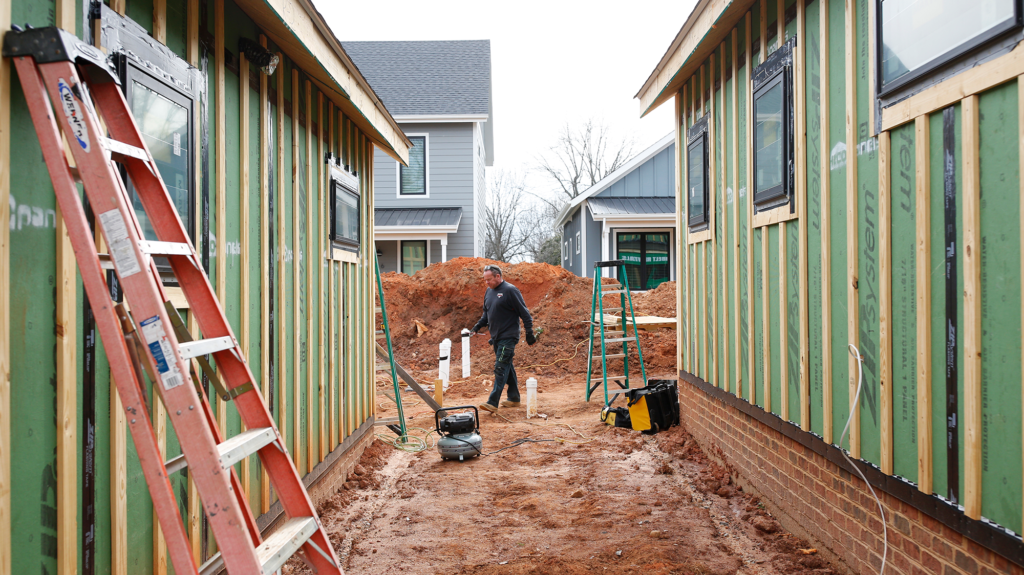 A man stands between two buildings under construction.