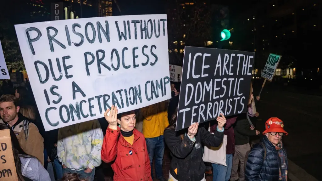 Protesters hold signs that read,