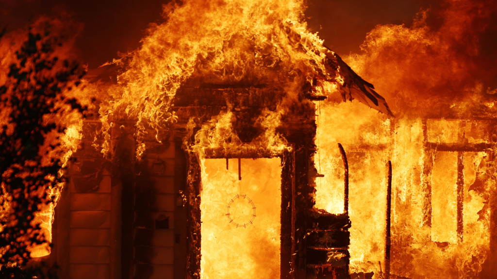 Bright orange flames engulf a burning house.