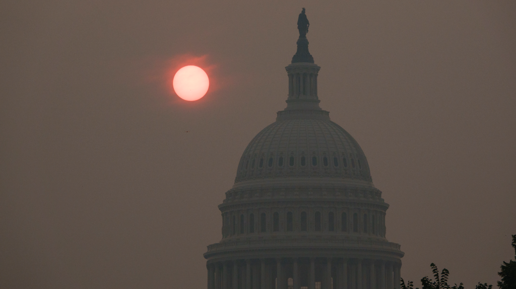 A red sun looms behind the silhouette of the US Capitol