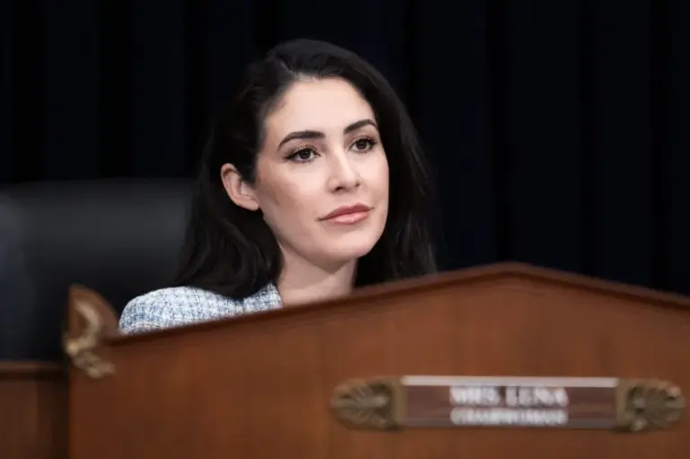 Rep. Anna Paulina Luna sits at a dais, with just her face and neck visible over the wooden desk