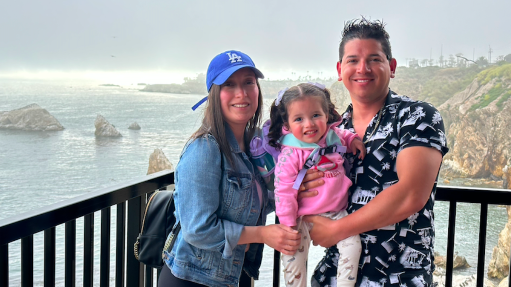 A group of three family members, a mom and a dad, posing together before a cliff