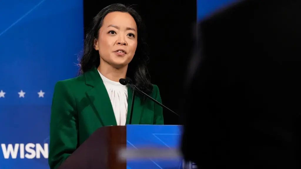 Francesca Hong, an East Asian woman in a green suit, standing in front of a podium