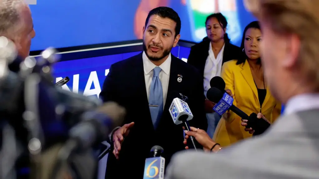 Democratic Senate candidate Abdul El-Sayed stands in front of reporters holing out microphones