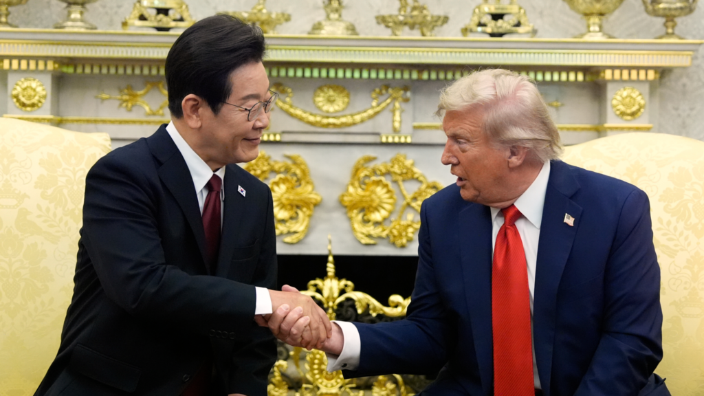 Donald Trump, right, shakes the right hand of South Korean President Lee Jae Myung in the Oval Office. Behind the pair is a fireplace and they are both sitting in chairs.