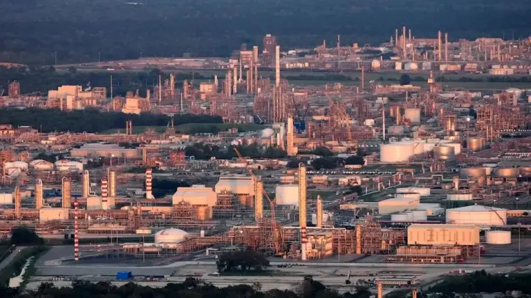 a landscape of chemical refineries seen from the air near days end with soft sunlight illuminating the structures