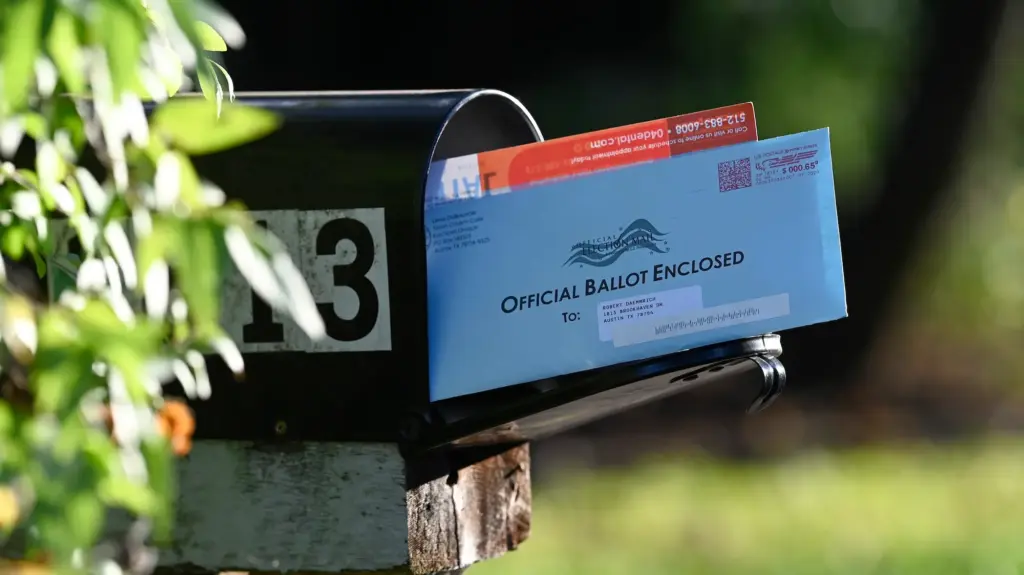A mail-in ballot sticking out of a mail box.