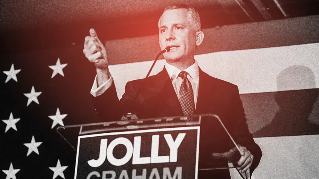 David Jolly, a politician in a suit at a podium, addresses a crowd at a campaign event. Overlaid on the image is a black, white, and red grained filter.