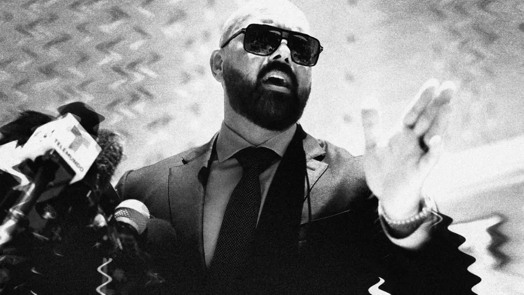 Joseph McBride, a bald man in a suit wearing sunglasses that has been treated with a warped filter on the background.