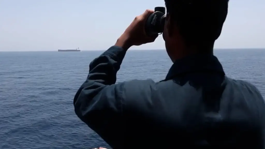 A US Sailor on the USS Rafael Peralta peers at an oil tanker as it enforces the maritime blockade.