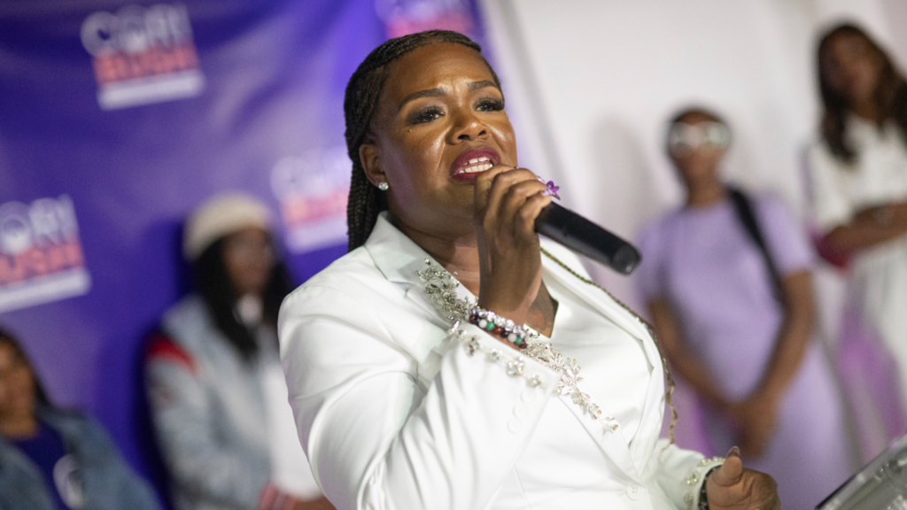 Cori Bush gives a speech wearing a white suit.
