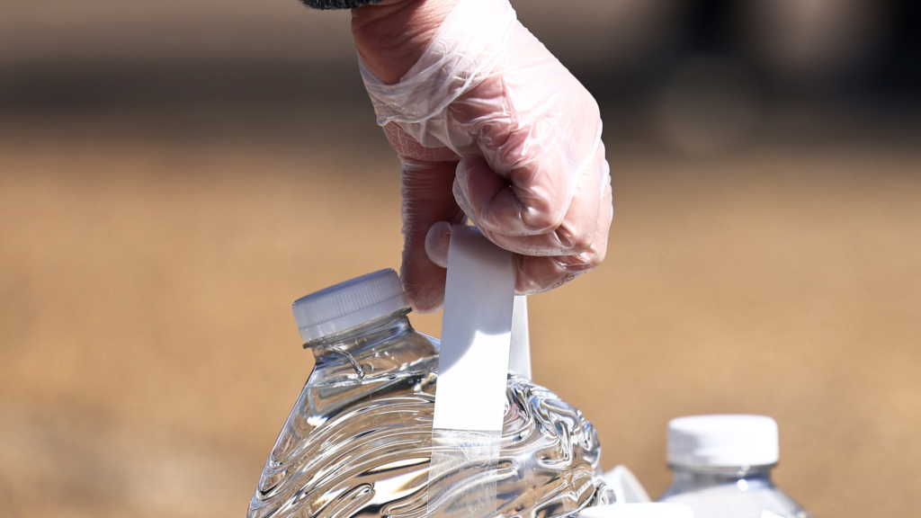 A volunteer grabs a gallon of water at a water and food distribution drive held by College Hill Baptist Church and the World Central kitchen on March 07, 2021 in Jackson, Mississippi.