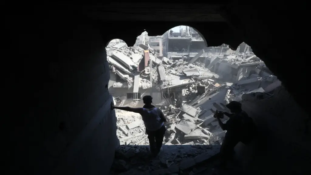 A person standing in a destroyed building looking out over rubble.