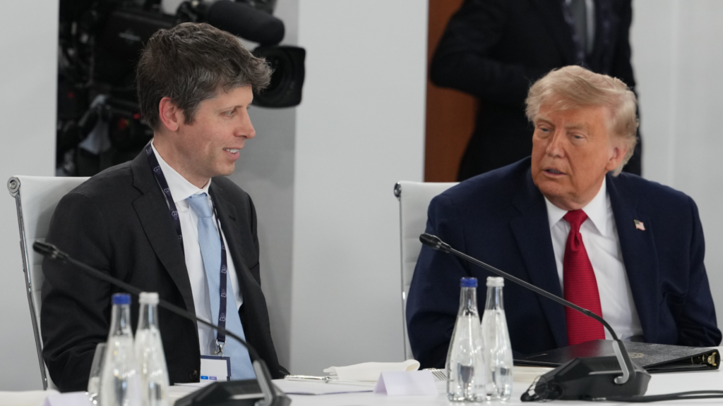 Donald Trump (right) and Sam Altman (left) are speaking with each other. They are wearing suits and sitting at a white table with microphones pointing off to the side to the right.