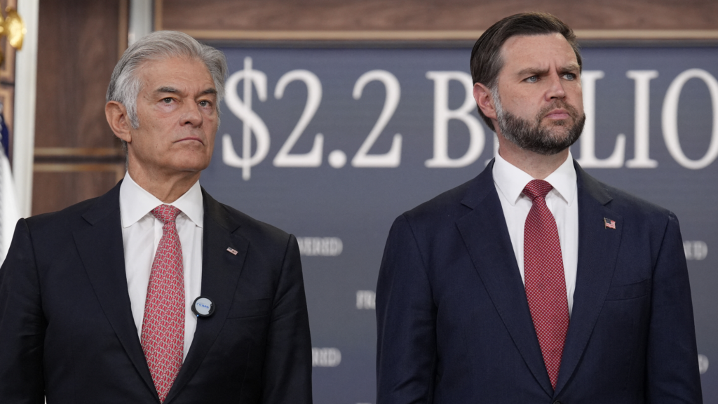 JD Vance and Mehmet Oz in front of a banner that says $2.2 Billion