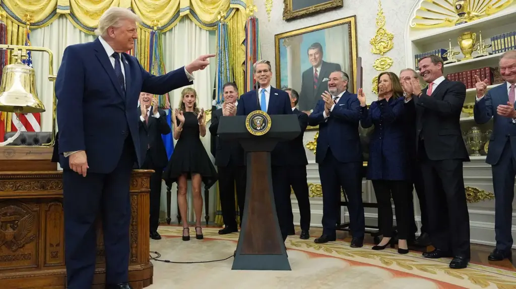 Donald Trump points at SEC commissioner Paul Atkins in the Oval Office, with a phalanx of clapping people alongside them.