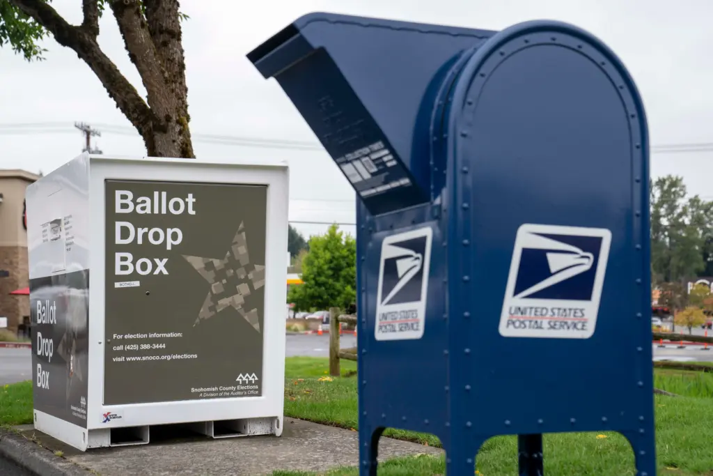Blue mail box near a large ballot drop box.