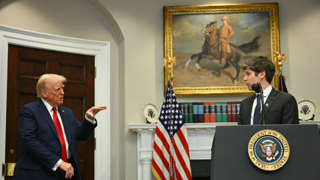 Sam Altman (right) is standing at a podium with a microphone. Donald Trump (left) is speaking to Altman. Trump is holding is hand out ahead of him and flat, parallel with the floor. They are in a room at the White House.