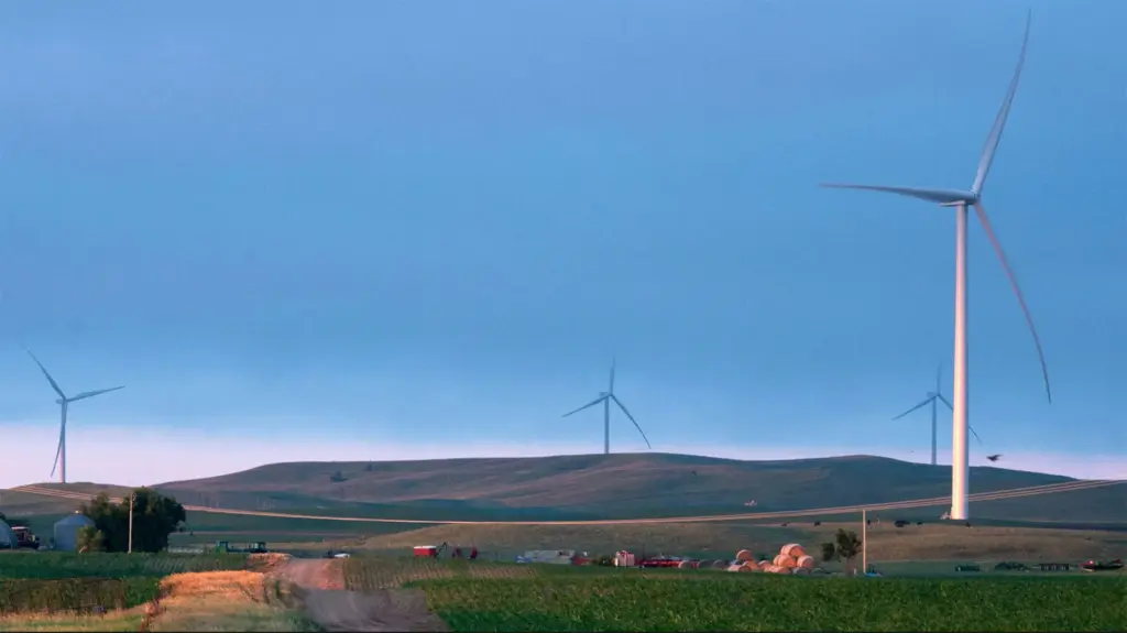 Wind turbines on hills near a farm and power lines.