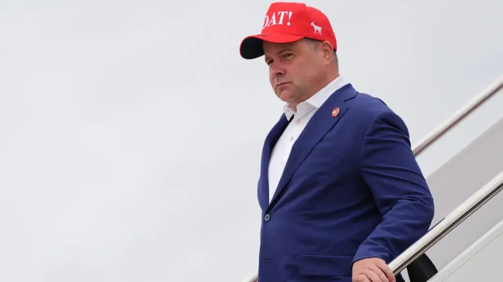 Federal Housing Finance Agency Director Bill Pulte exiting a plane wearing a suit and large red hat.