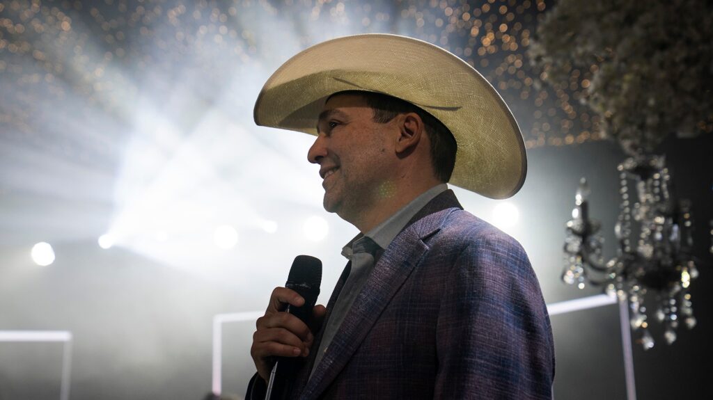 Man in a cowboy hat holding a microphone.