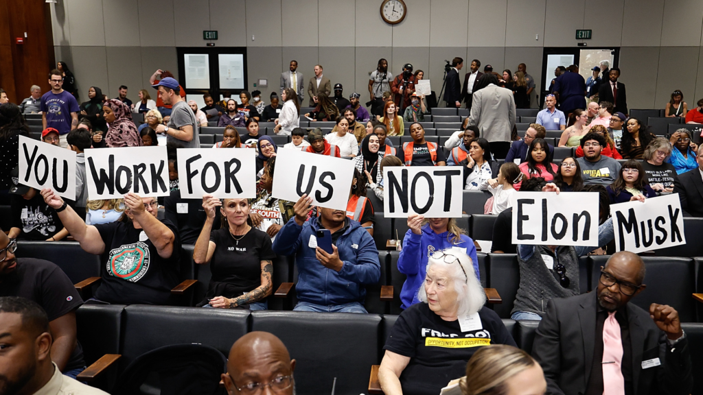 People hold up signs reading