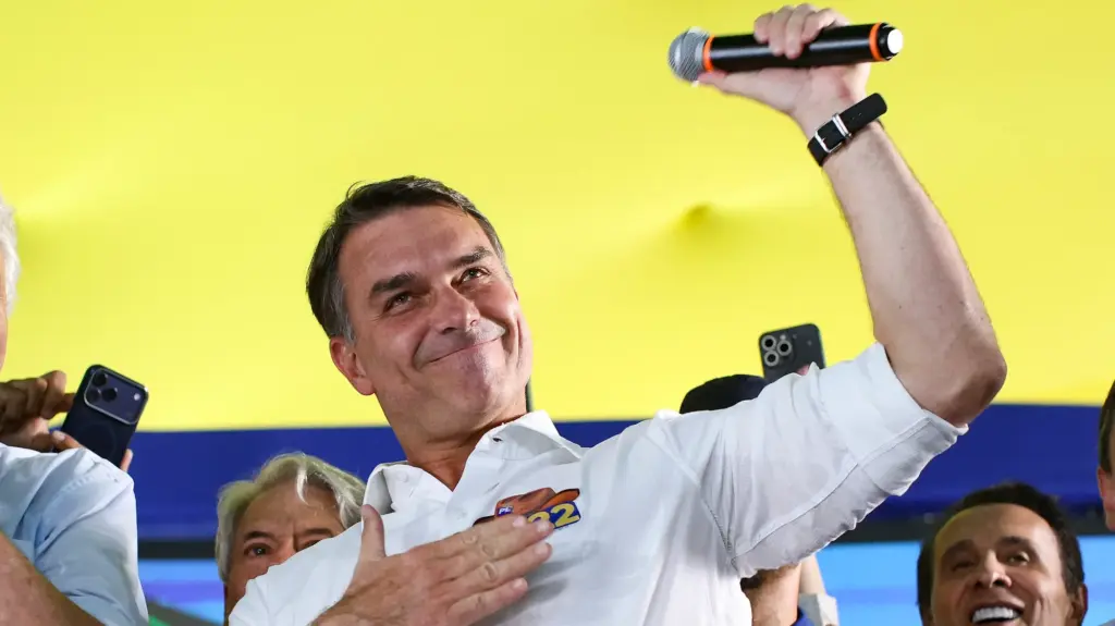 A man with a white shirt, holds up a microphone in triumph.