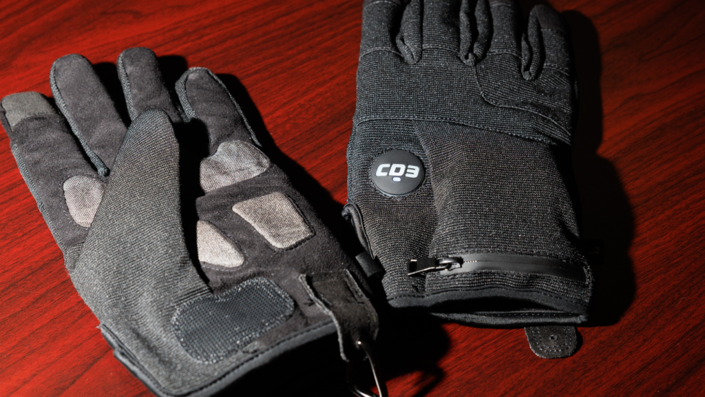 A pair of black fabric shock gloves on a varnished wooden surface.