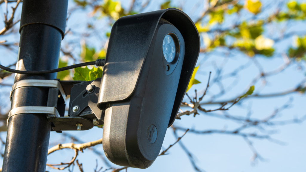 A close-up view shows a solar-powered Flock Safety automated license plate reader (ALPR) public safety surveillance camera mounted on a utility pole in a commercial parking lot in American Fork, Utah, United States, on September 20, 2026.